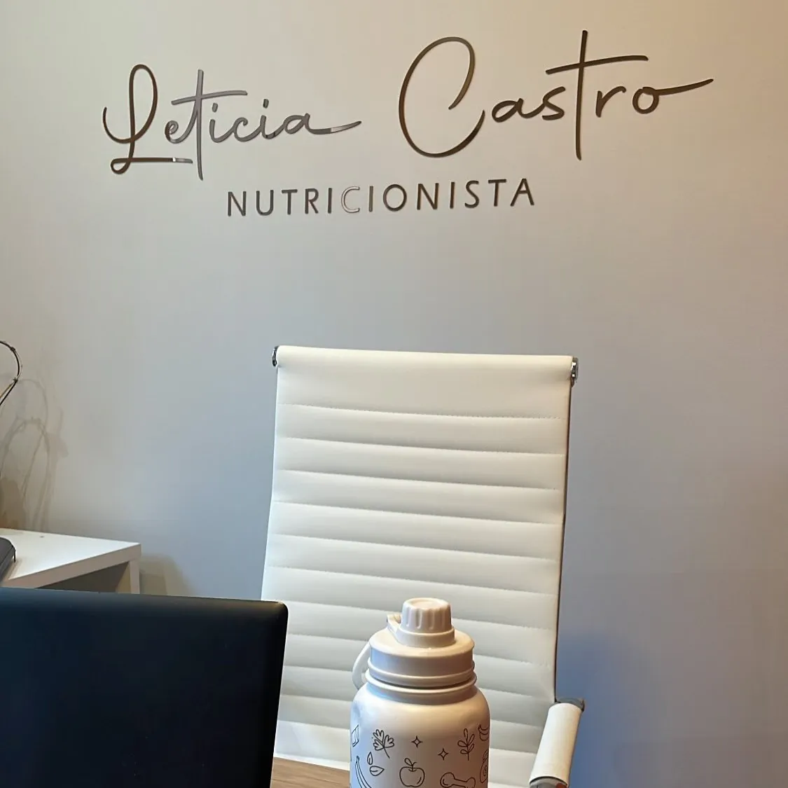 Mesa de atendimento com o nome Letícia Castro Nutricionista na parede